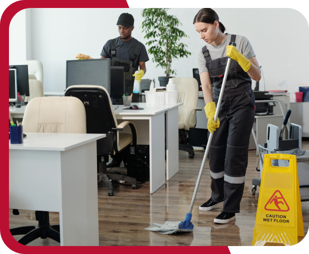 Two workers clean an office; a woman mops the floor, and a man tidies a desk. A "Caution Wet Floor" sign is visible.